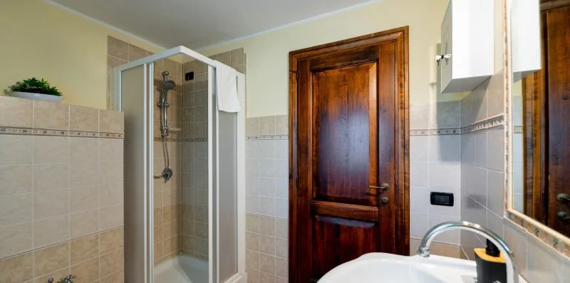 A tiled bathroom with a glass shower and a wooden door.