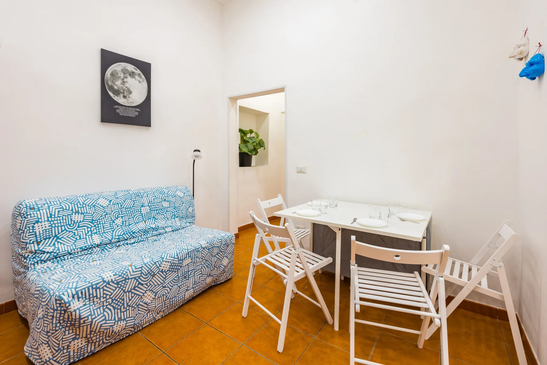 A bright dining area with a table and chairs beside a patterned sofa.