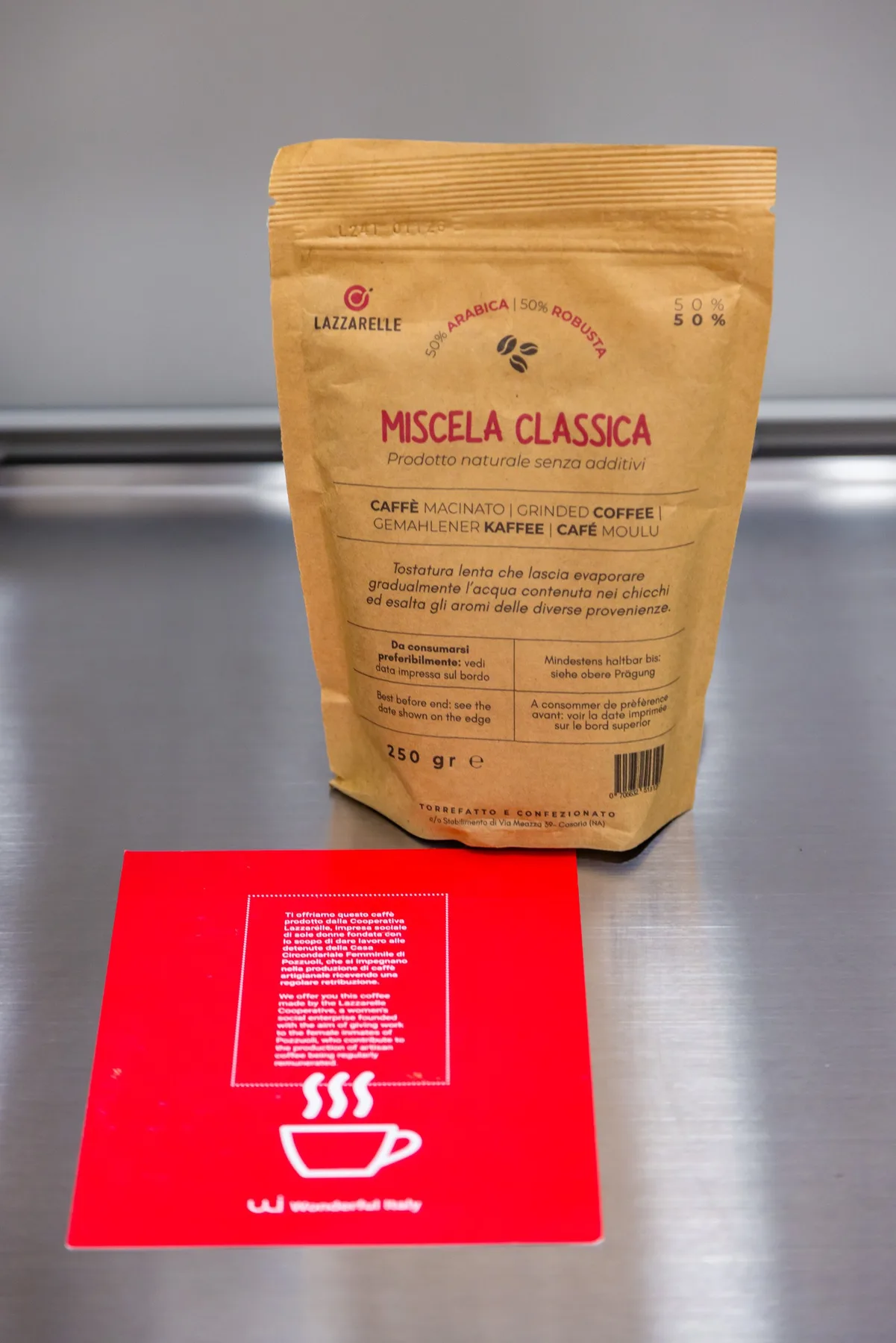A bag of coffee sits on a stainless-steel counter beside a red card.