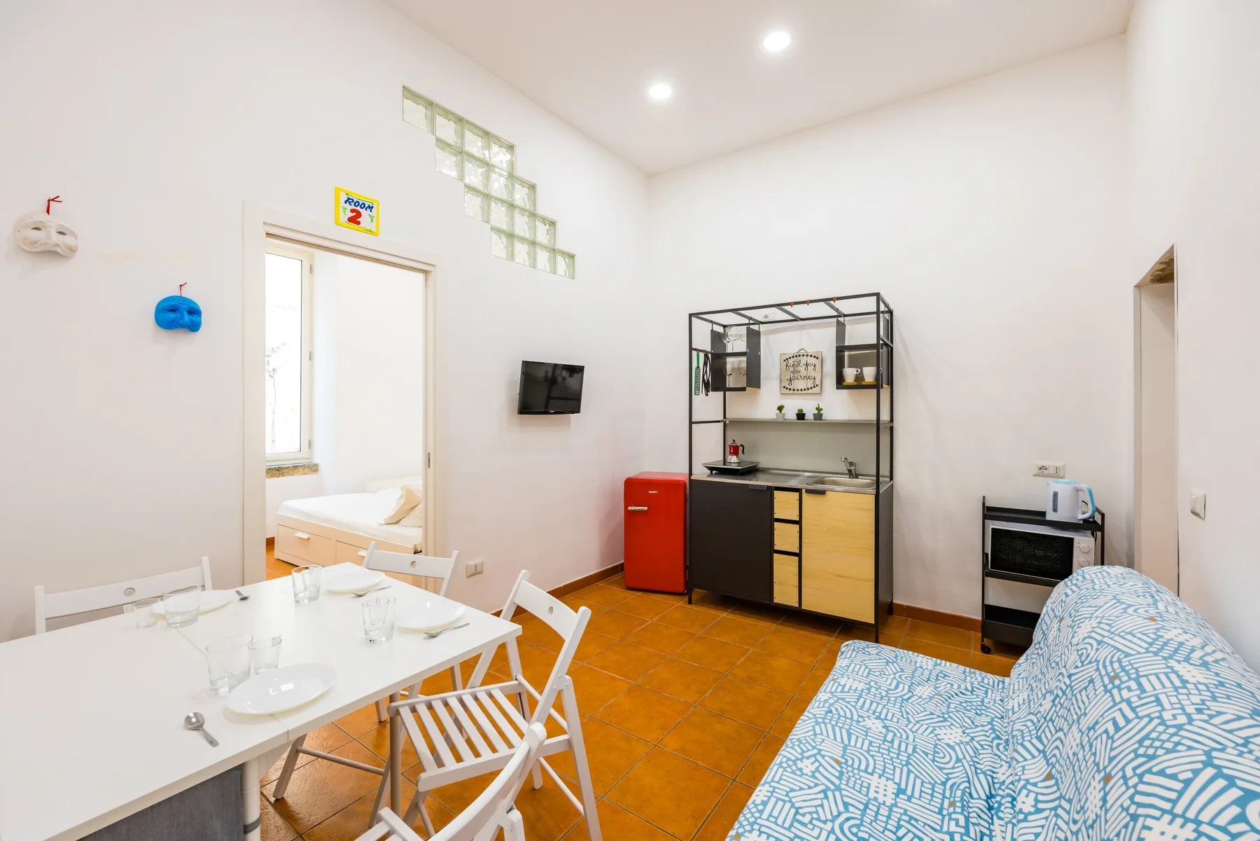 A bright dining and living area with a white table, seating, and a kitchen counter.