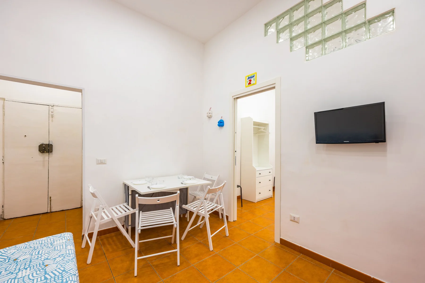 A dining area with a table and chairs sits beside an open doorway.