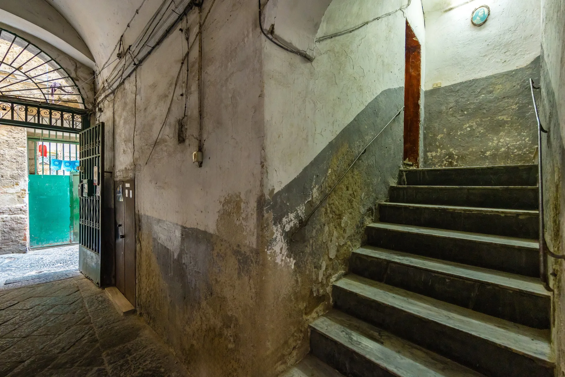 A worn interior passage leads to a stone staircase beside an open entrance.