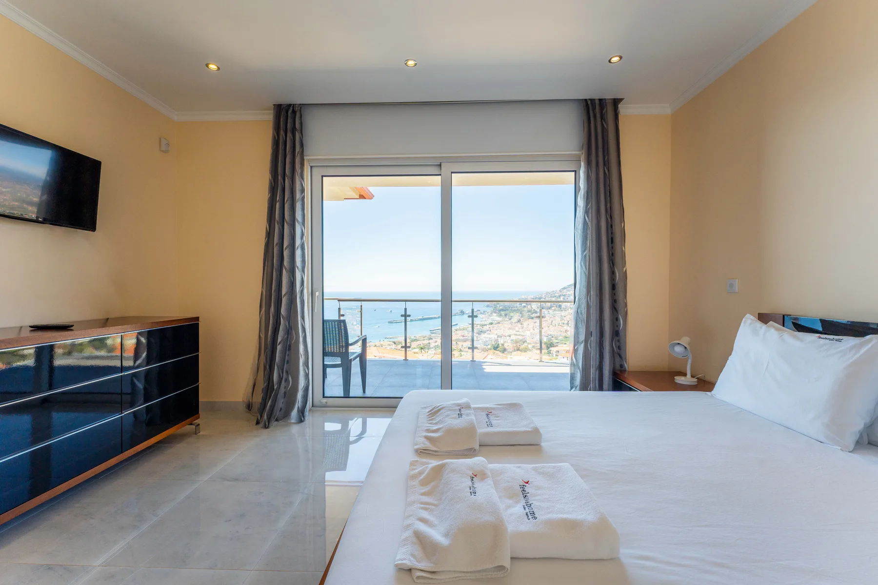 Un dormitorio con una cama grande junto a puertas correderas de cristal que dan a un balcón.