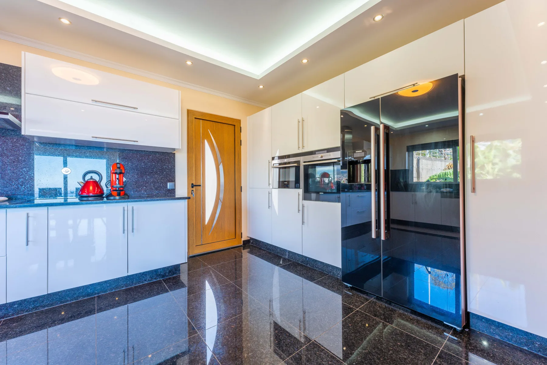 Una cocina moderna con gabinetes blancos y un refrigerador negro.