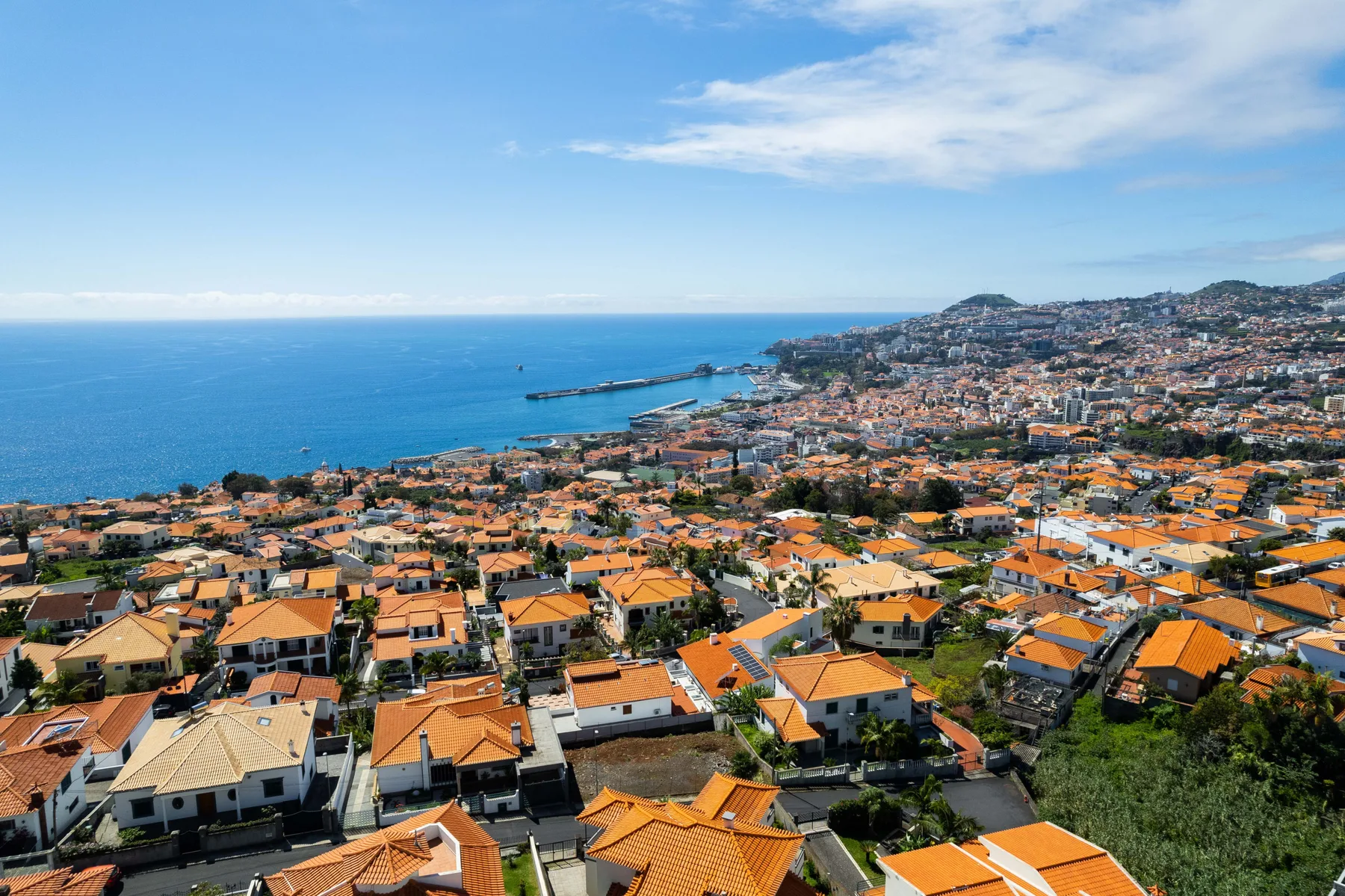 Una ciudad costera se extiende por una ladera junto al mar azul.