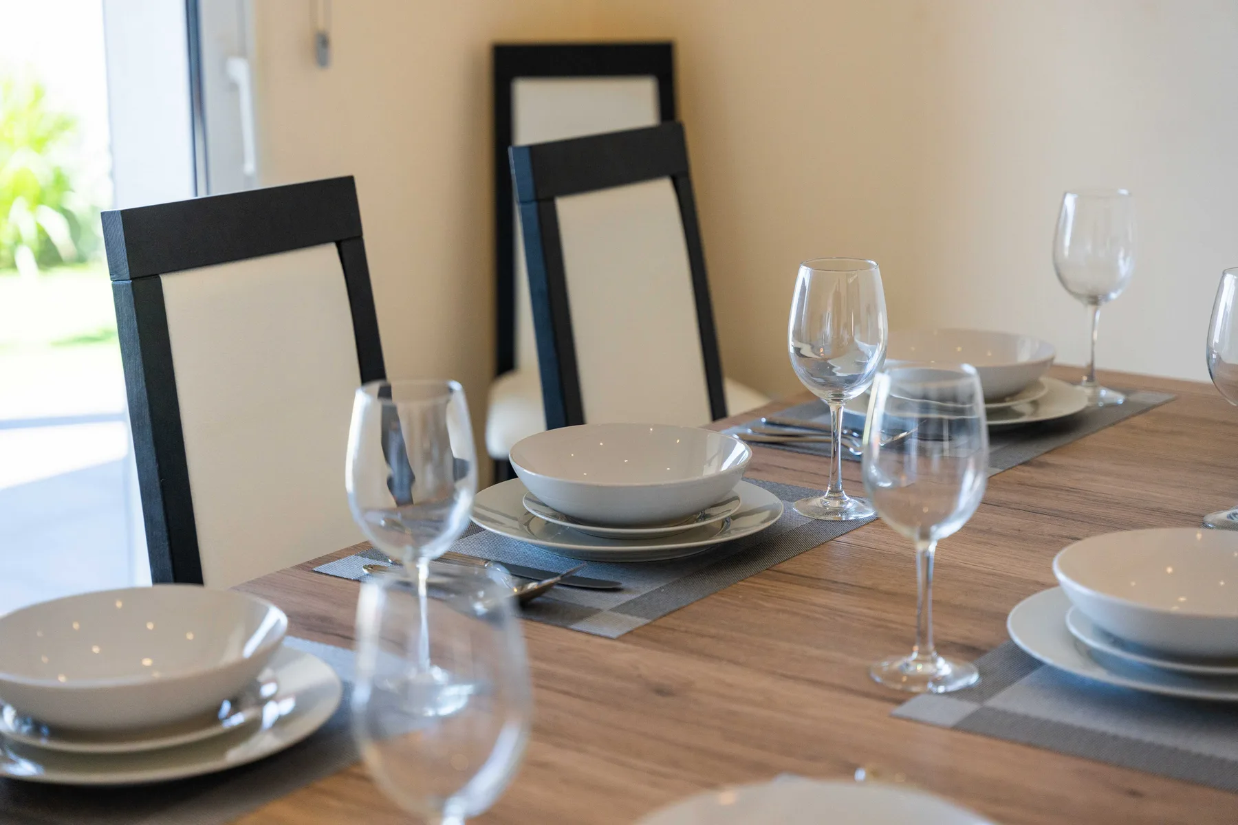 Comedor con platos y copas dispuestos sobre una mesa de madera.