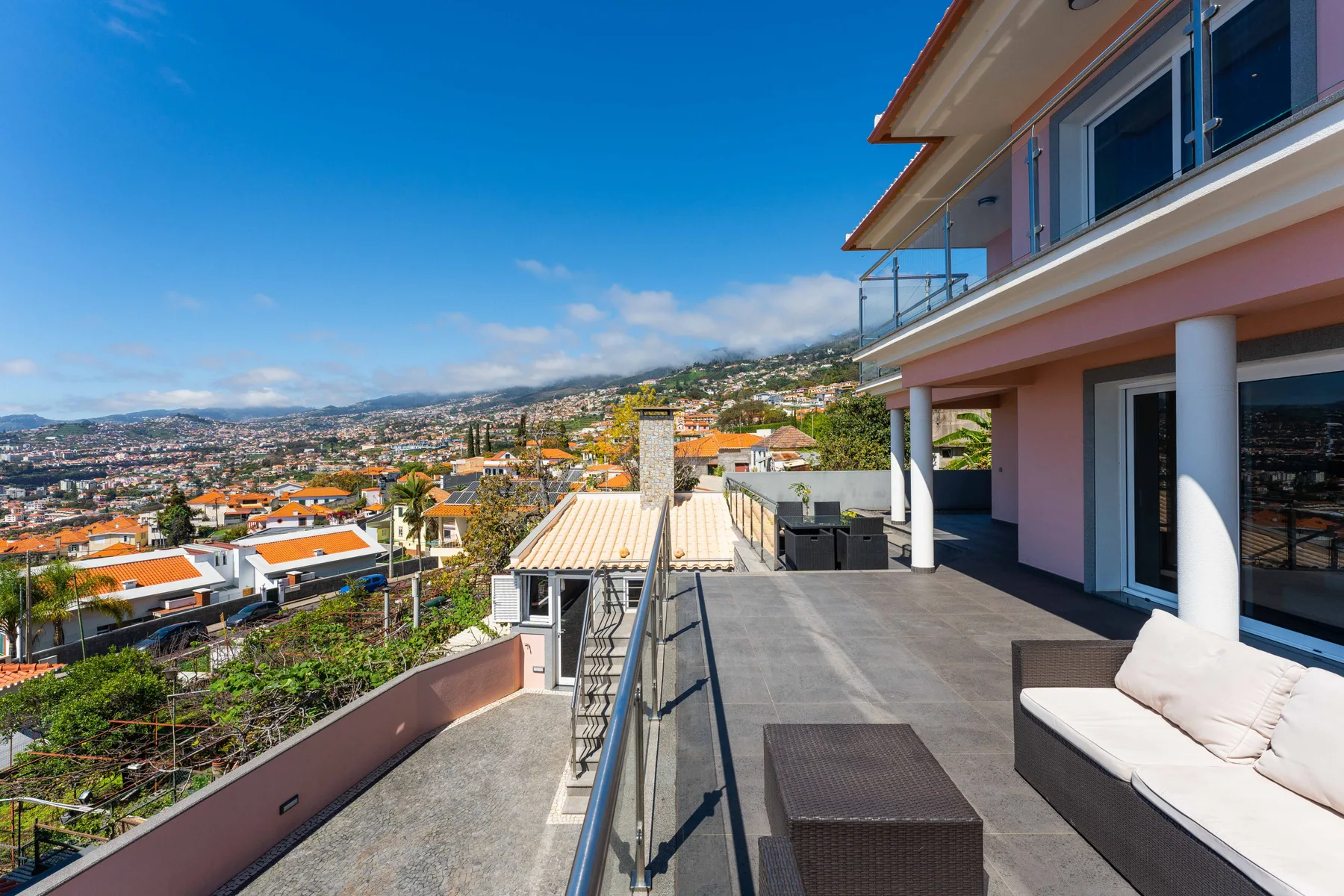 Una terraza en la azotea con asientos al aire libre tiene vistas a una ciudad y colinas.