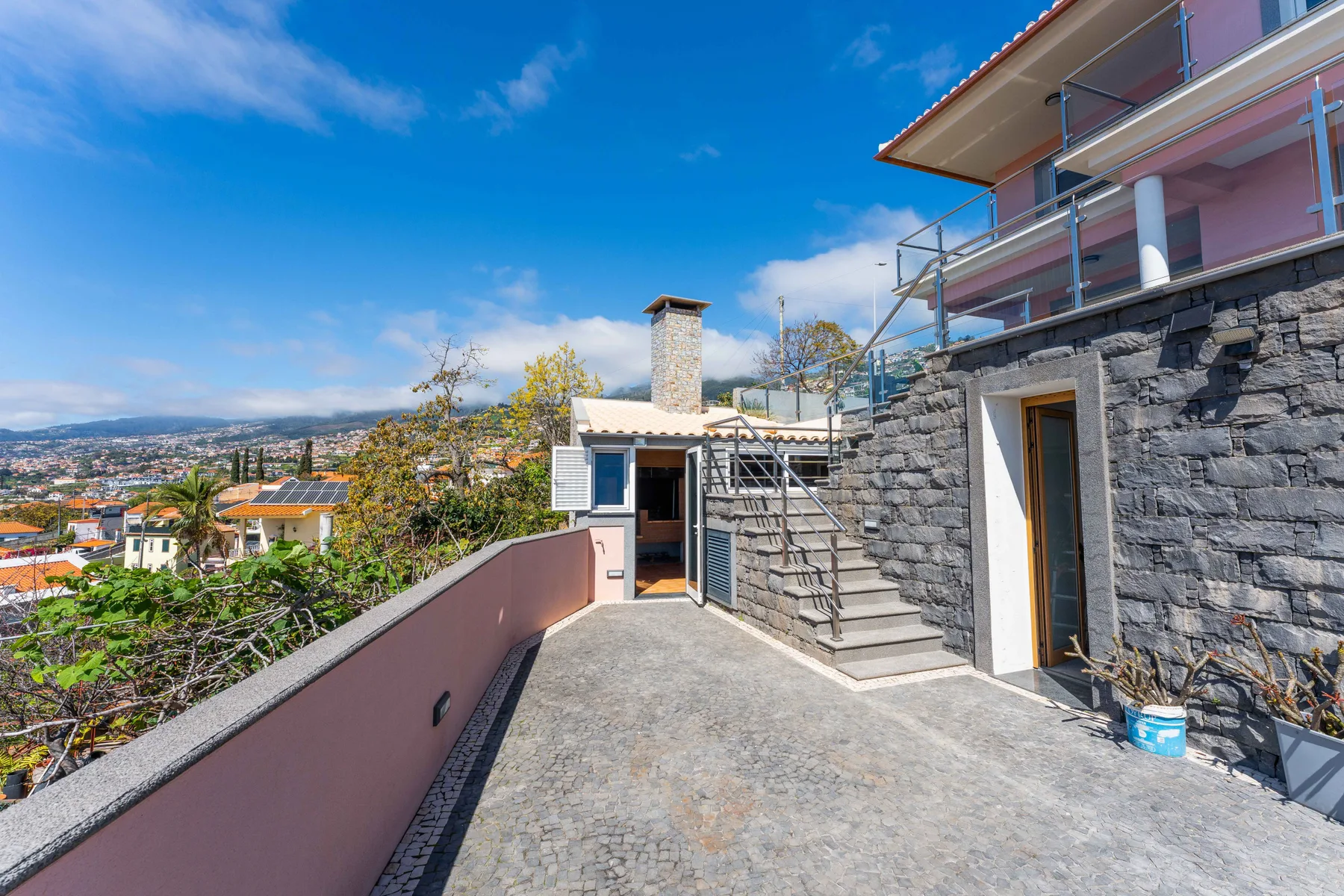 Una terraza pavimentada con piedra junto a una casa da a un barrio en la ladera.