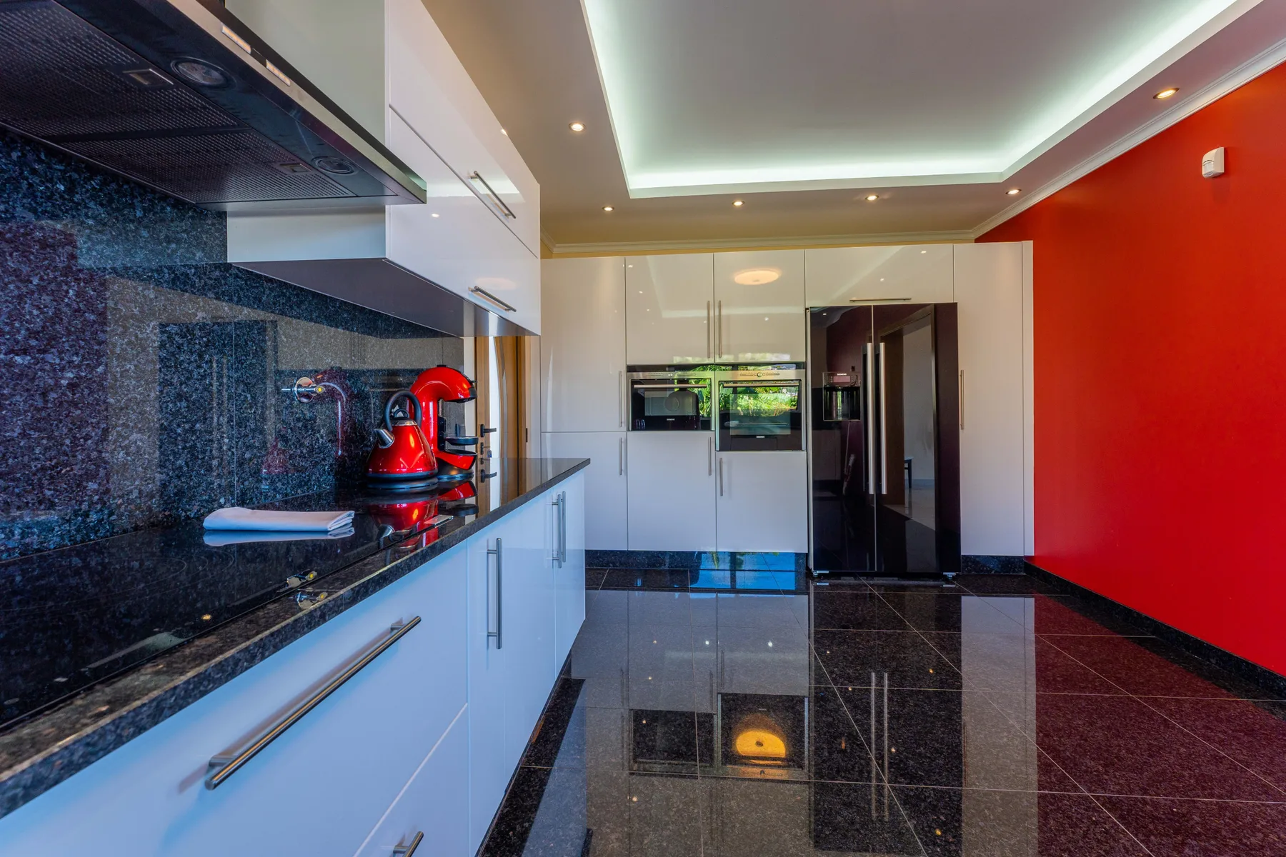 Una cocina moderna con armarios blancos y una encimera oscura.