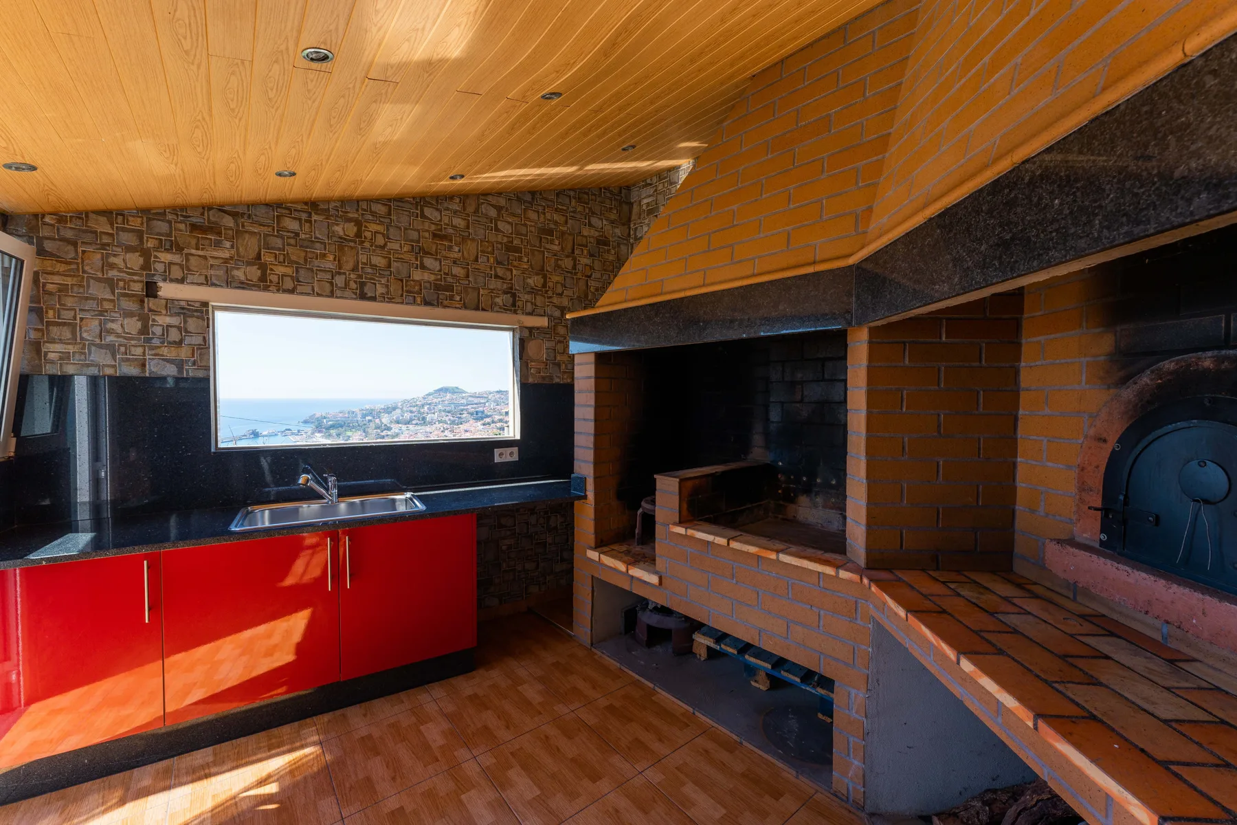 Una cocina con armarios rojos y una zona de barbacoa de ladrillo.