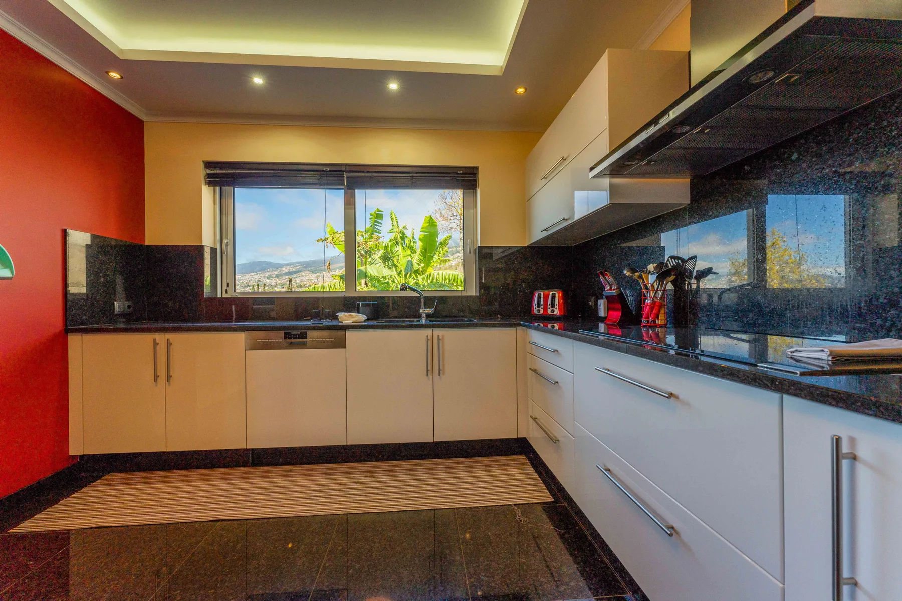 Una cocina moderna con muebles claros y una ventana con vistas a la vegetación.