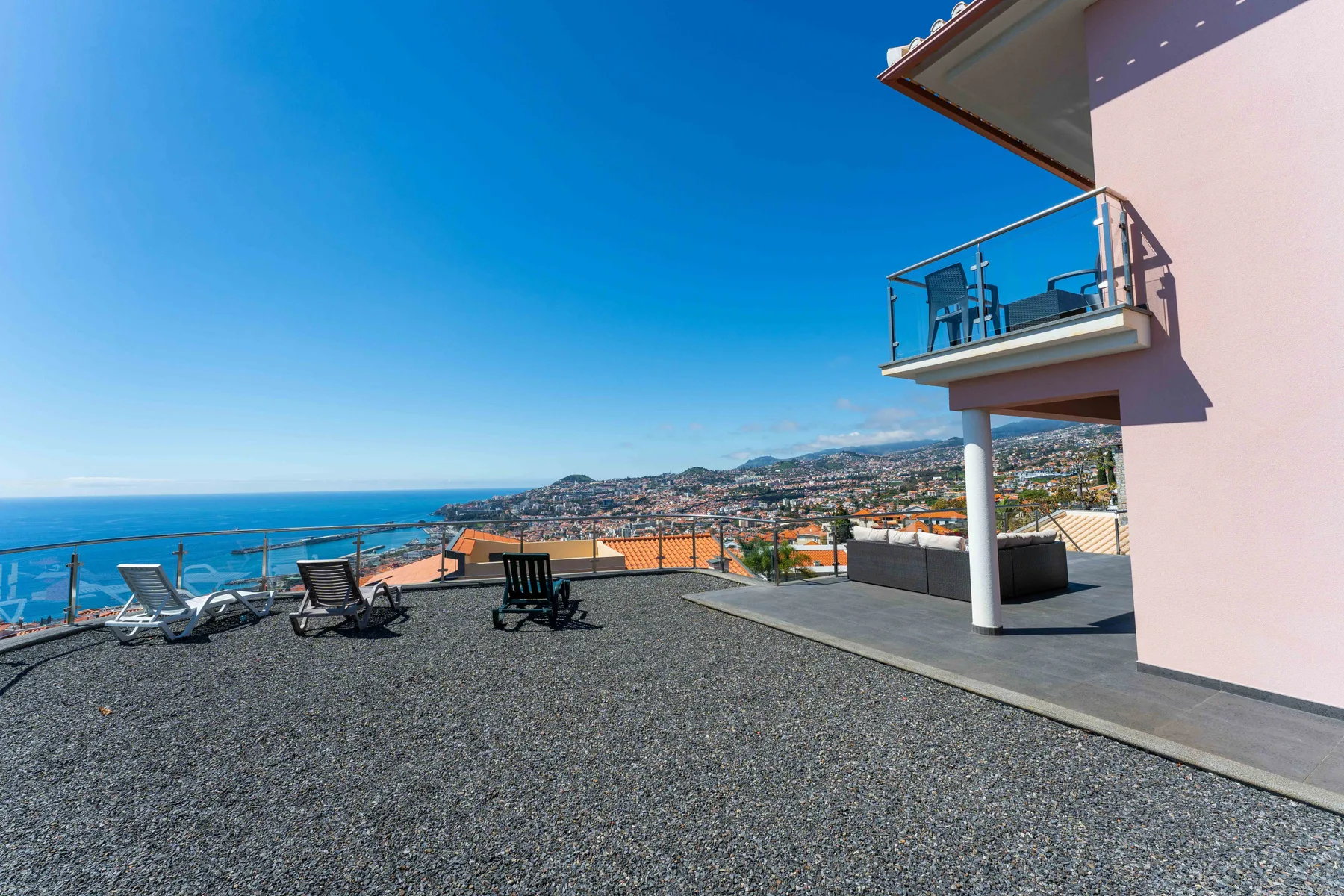 Una terraza en la azotea con vistas al mar y asientos al aire libre junto al edificio.