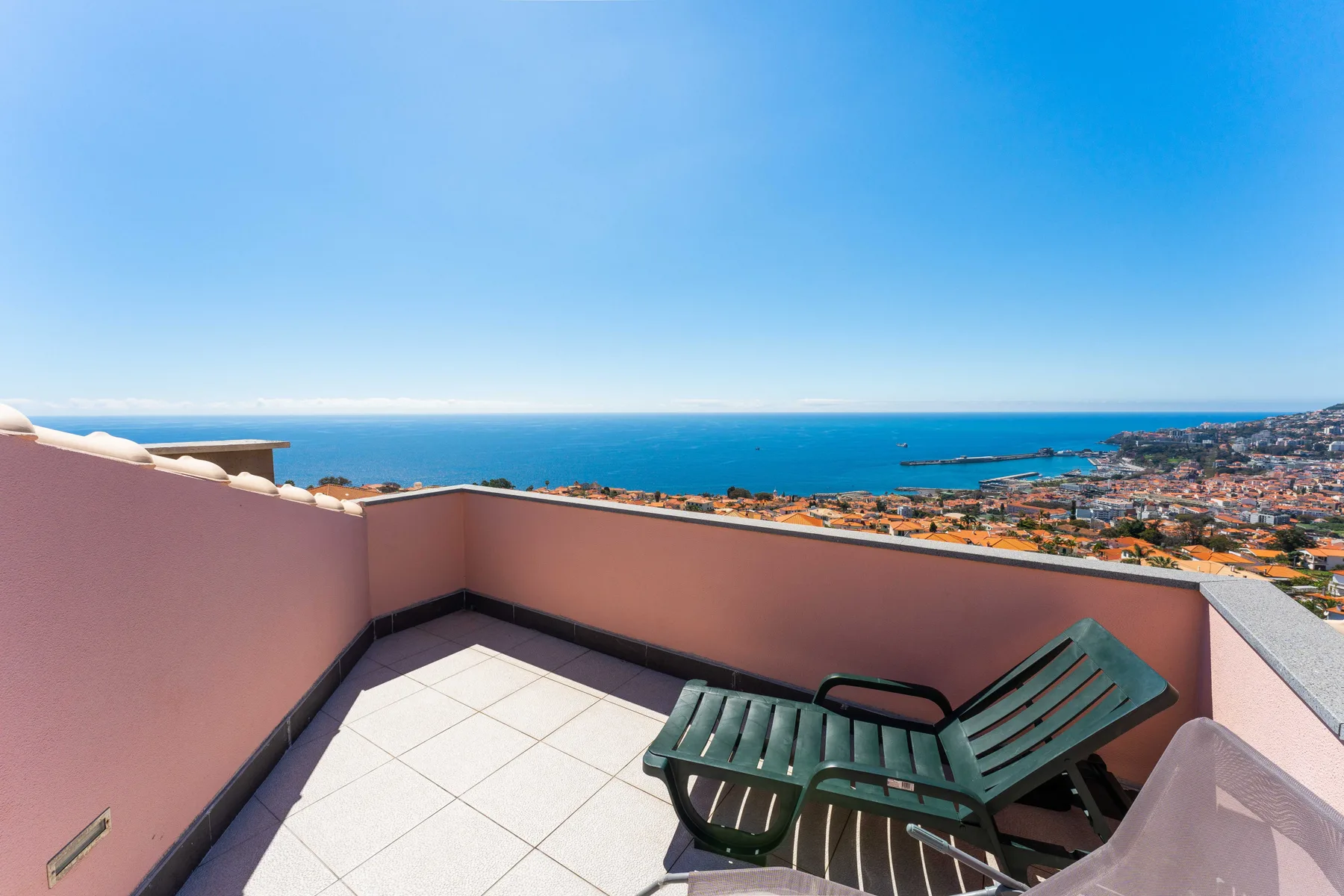 Una terraza de baldosas da al mar y cuenta con asientos reclinables al aire libre.