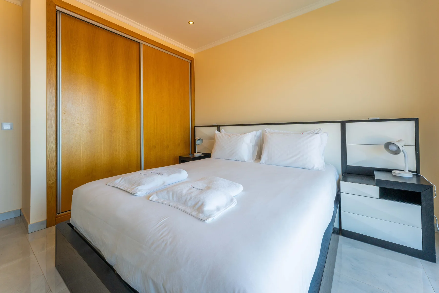 Un dormitorio con una cama bien tendida y puertas correderas de armario de madera.