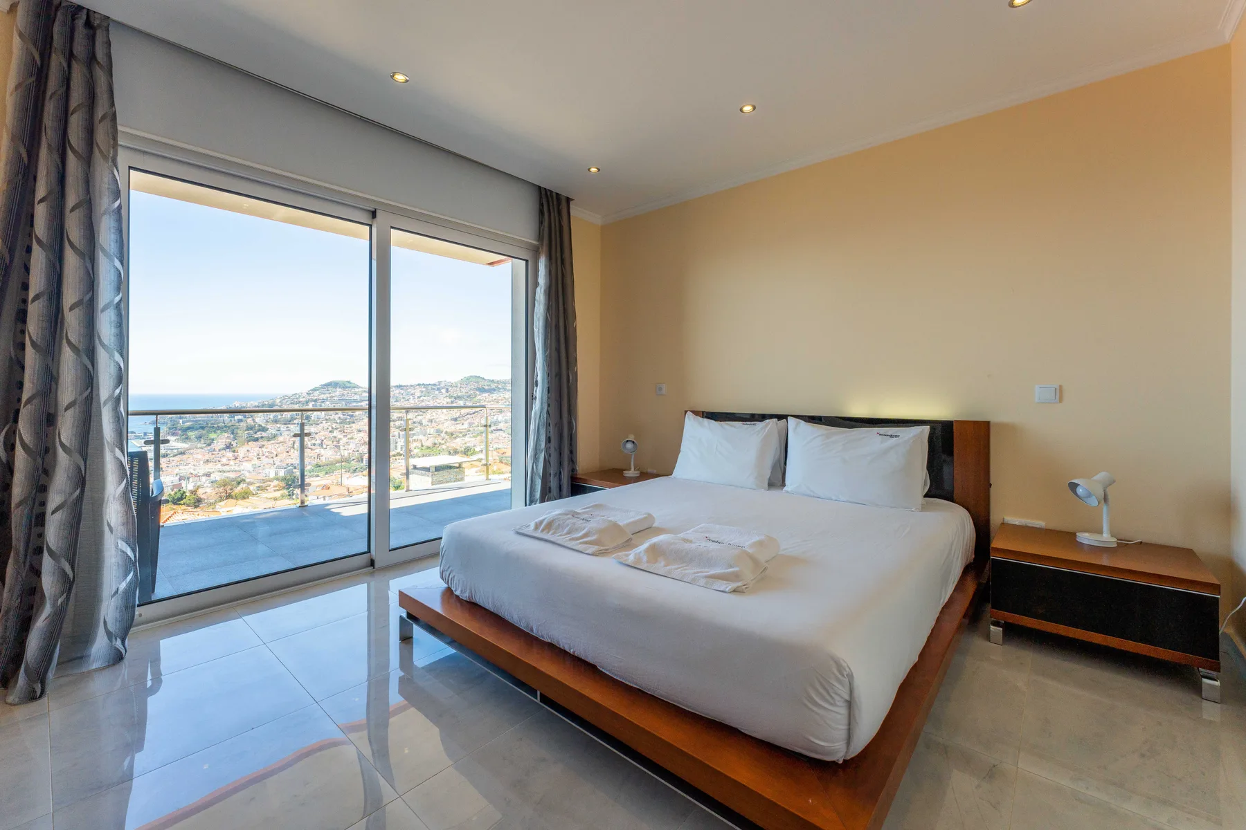 Dormitorio con una cama doble junto a grandes puertas correderas de cristal con vistas al paisaje.