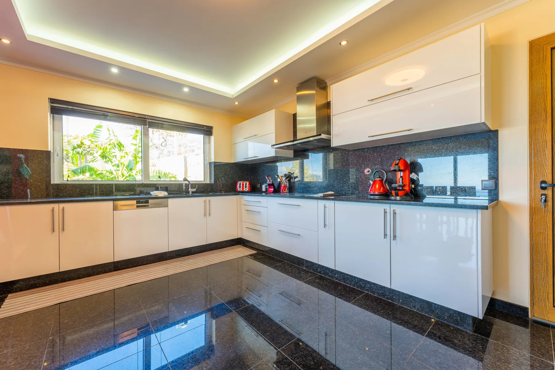 Una cocina moderna con muebles blancos y una encimera oscura.