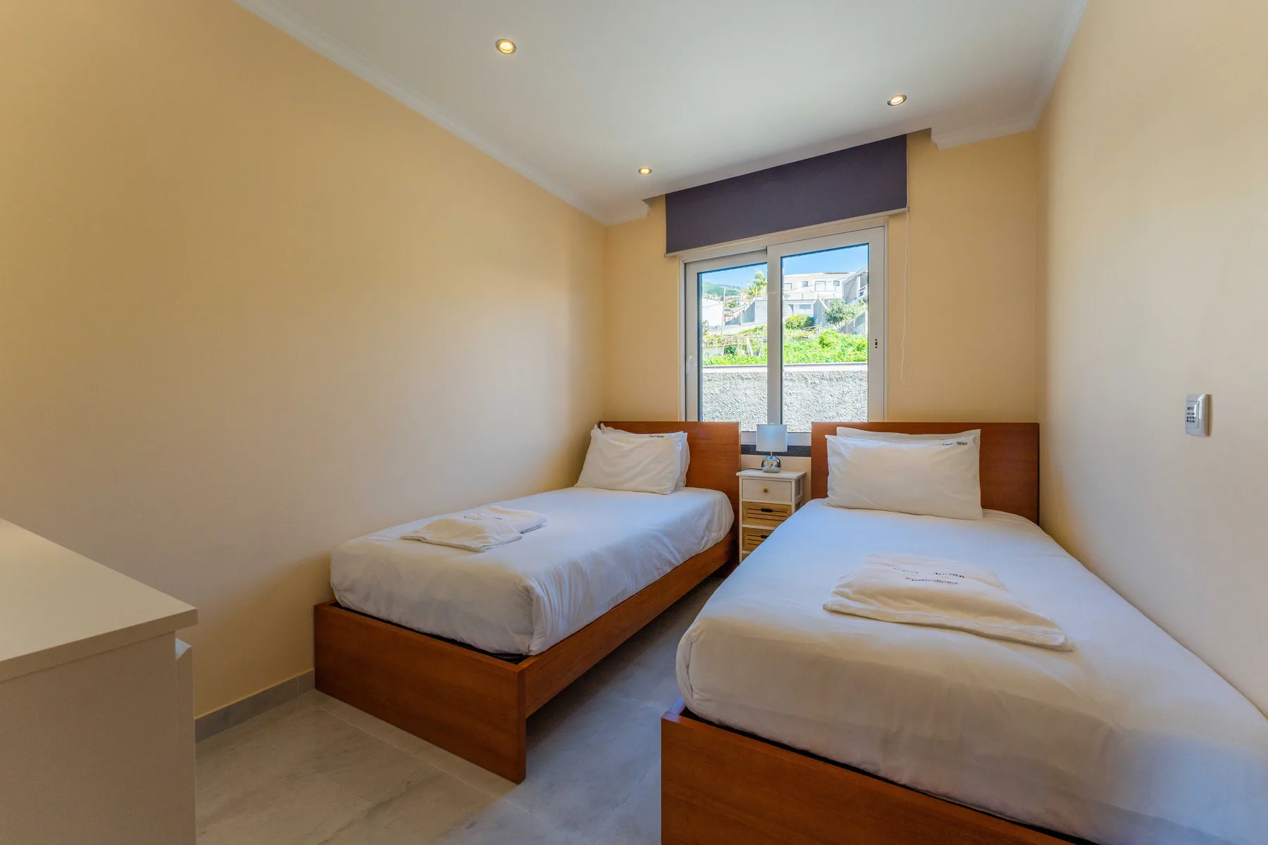Un dormitorio con dos camas individuales y una ventana con vistas a zonas verdes.