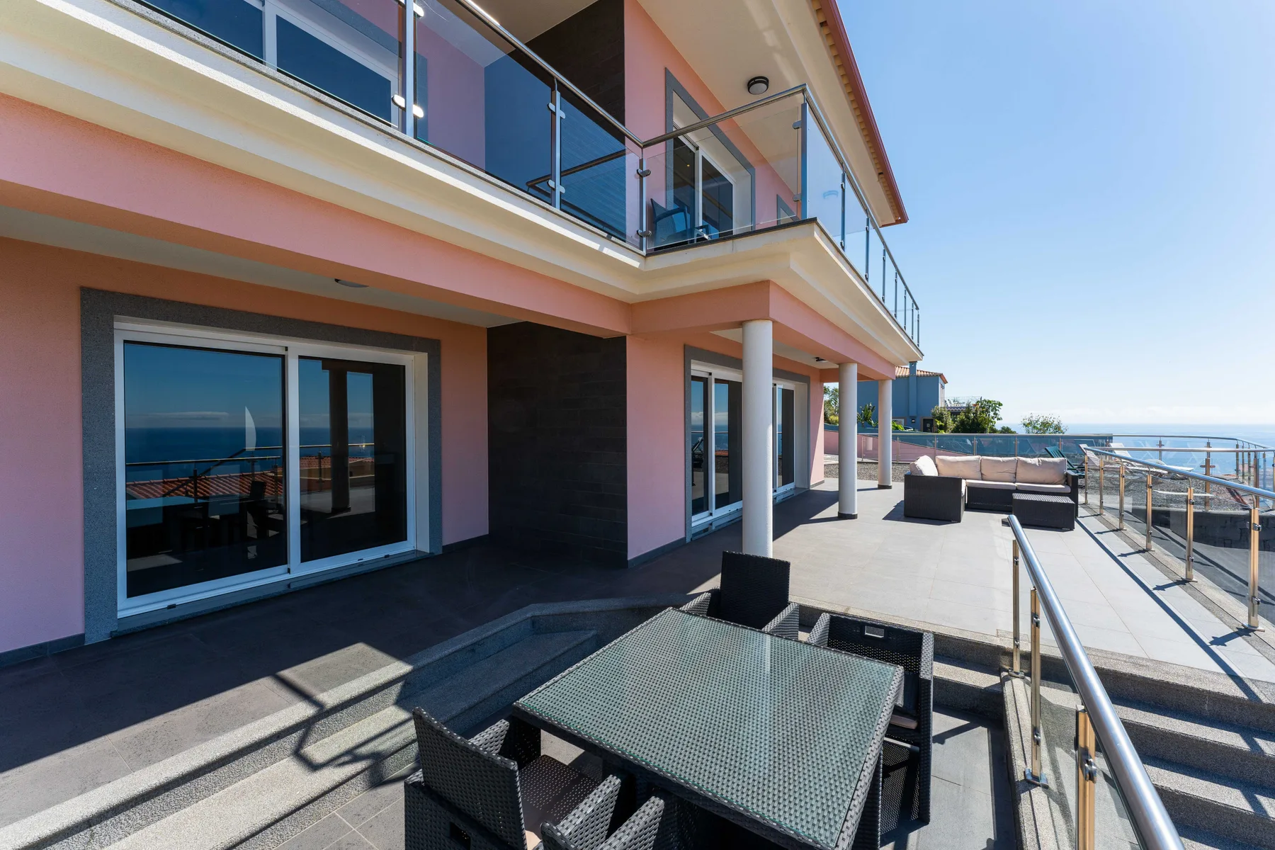 Una terraza exterior soleada con asientos tiene vistas al mar.