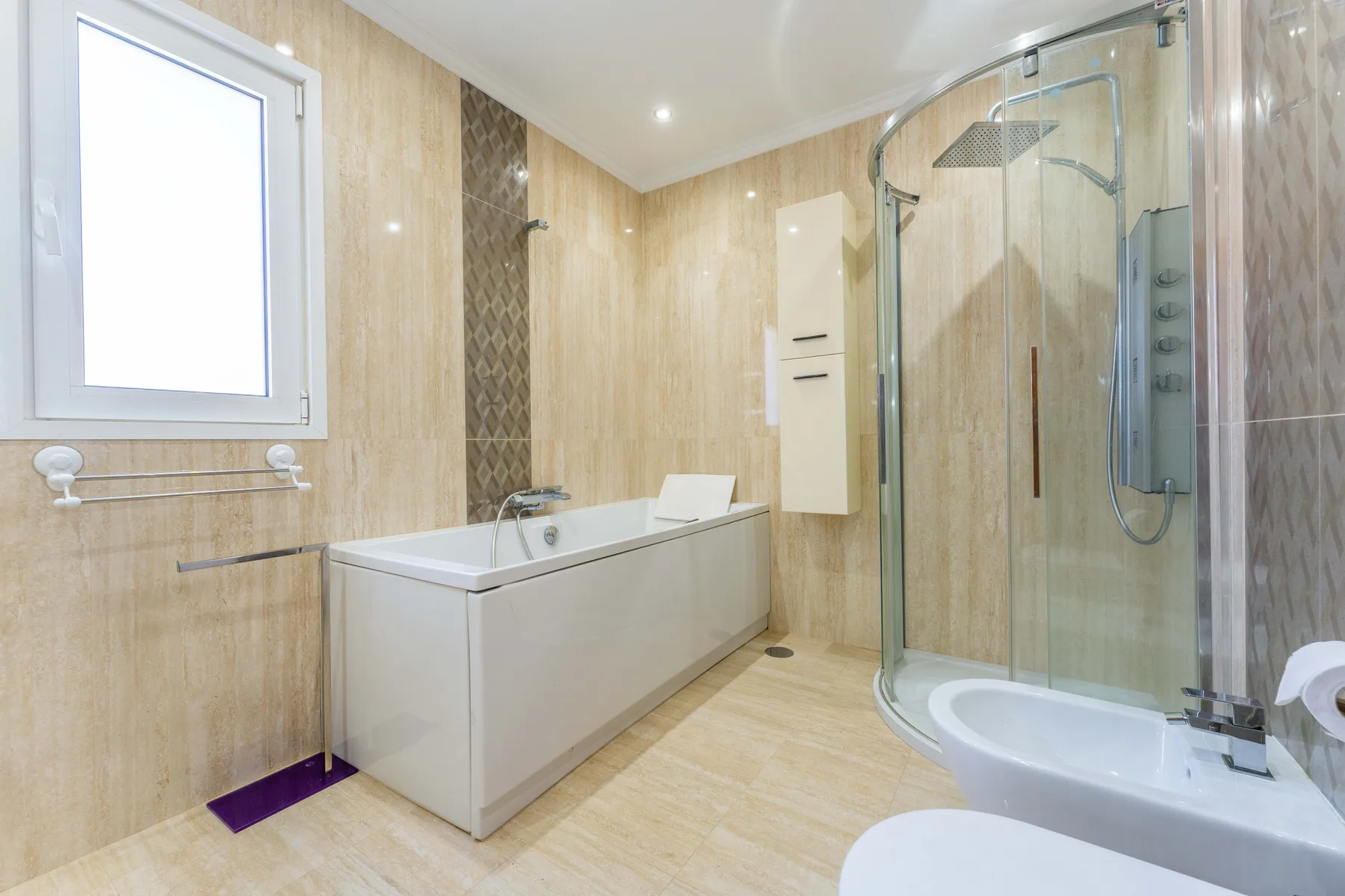 Un baño luminoso con bañera y ducha acristalada.