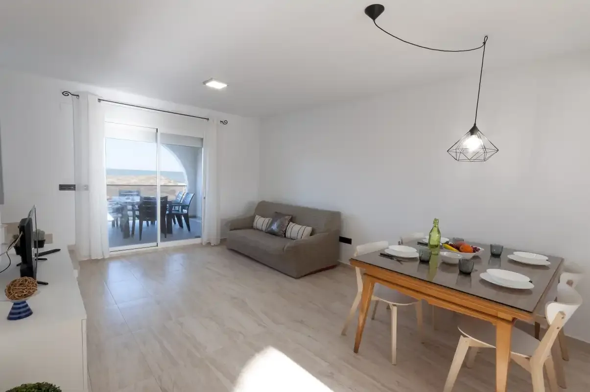A bright living and dining area with seating, a table, and sliding glass doors.