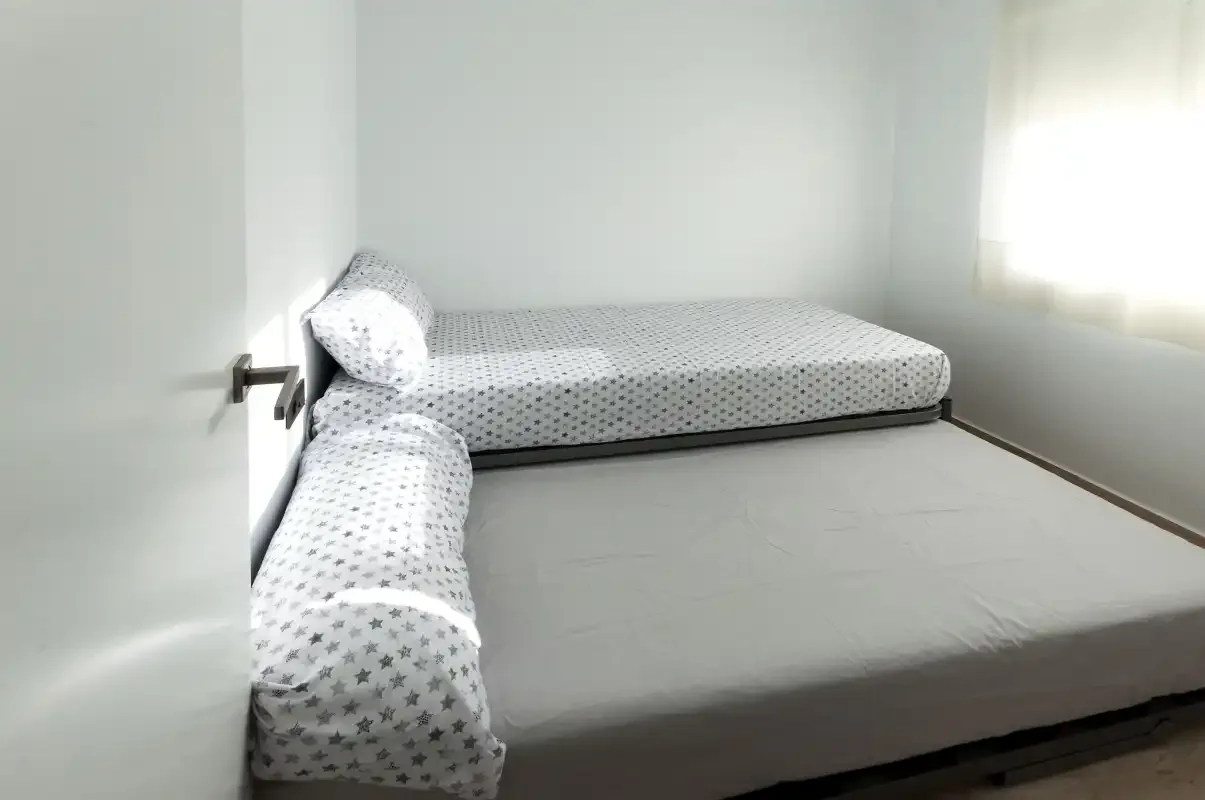 A bedroom with two beds and a bright window.
