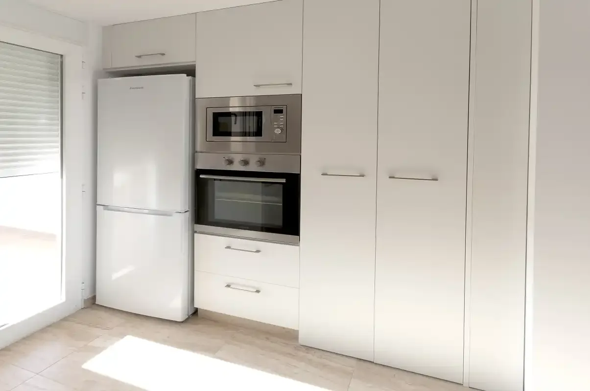 A bright kitchen with white cabinets and built-in appliances.