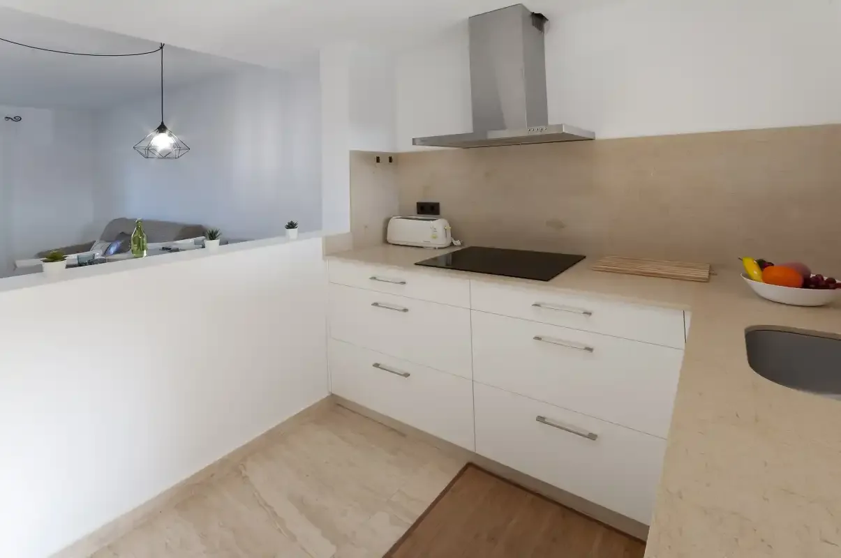 A modern kitchen with white cabinets, a dark cooktop, and a countertop.