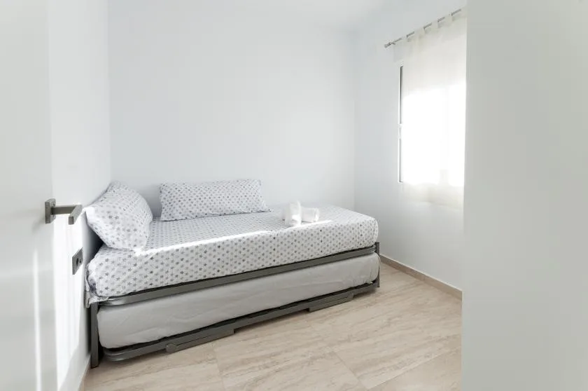 A bright bedroom with a bed and a sunlit window.