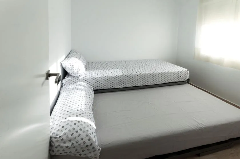 A simple bedroom with two mattresses arranged along the walls.