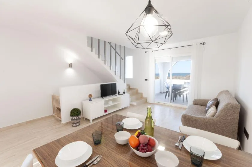 A bright living room with a dining table, seating, and sliding glass doors to a balcony.