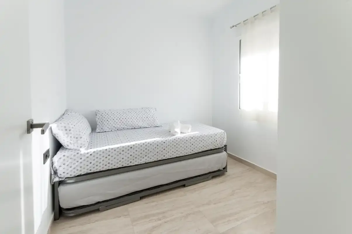 A bright bedroom with a daybed and a window with a sheer curtain.