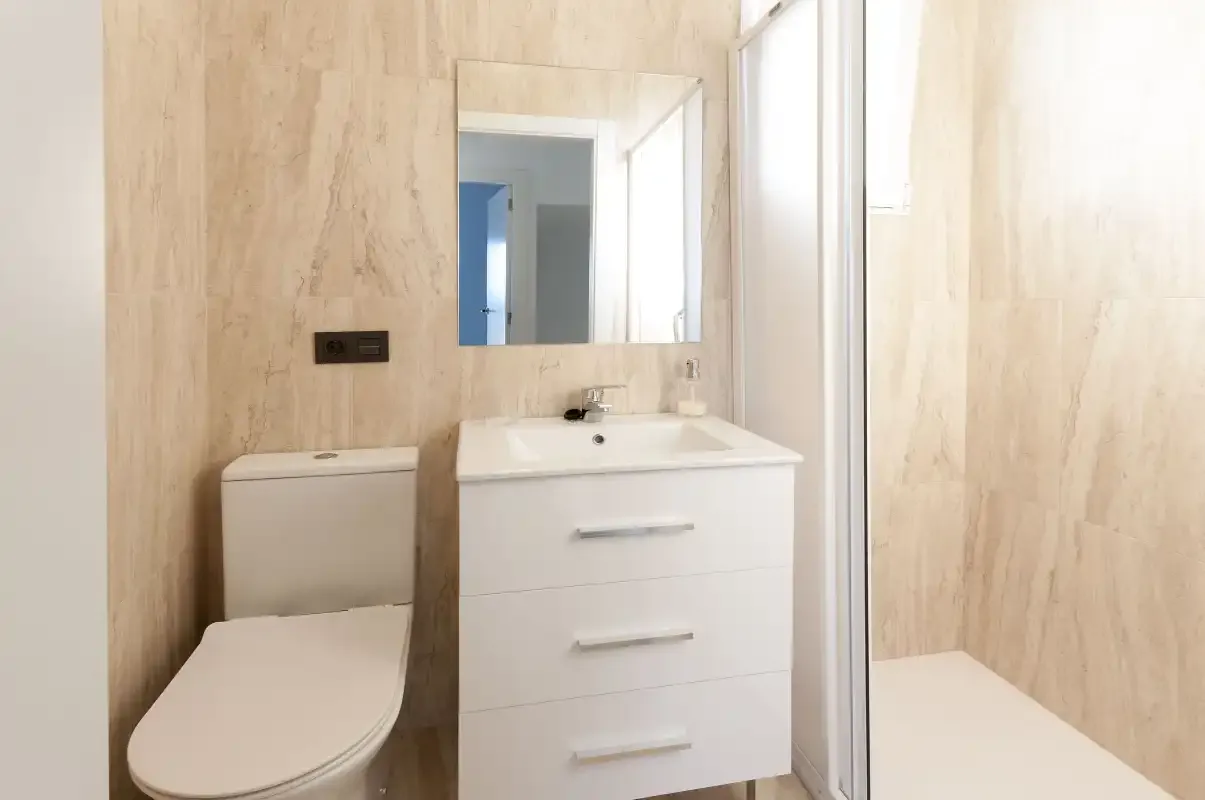 A bathroom with a sink vanity, mirror, and shower.