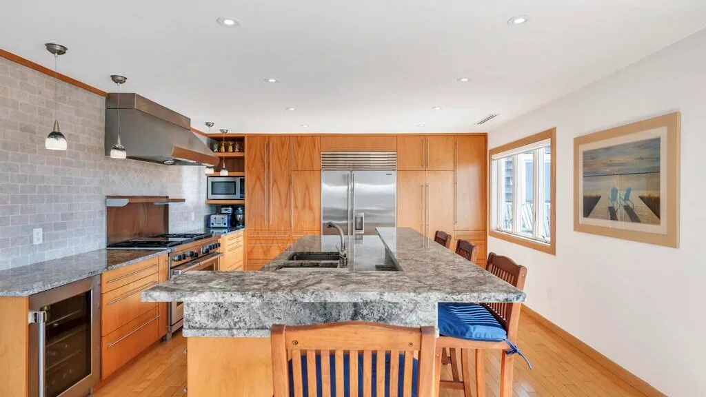 A spacious kitchen with wooden cabinetry and a large stone island.