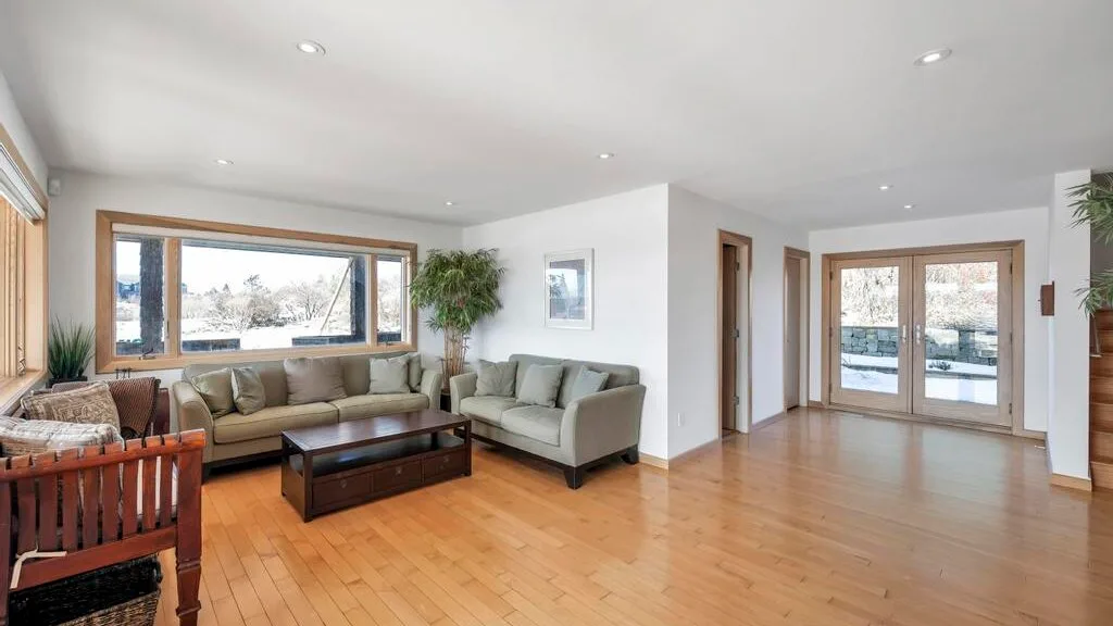 A bright living room with seating, a coffee table, and large windows.