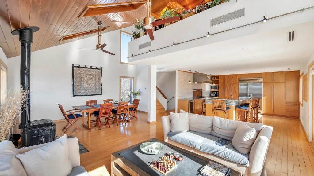 An open-plan living and dining room with a sofa, dining table, and wood stove.