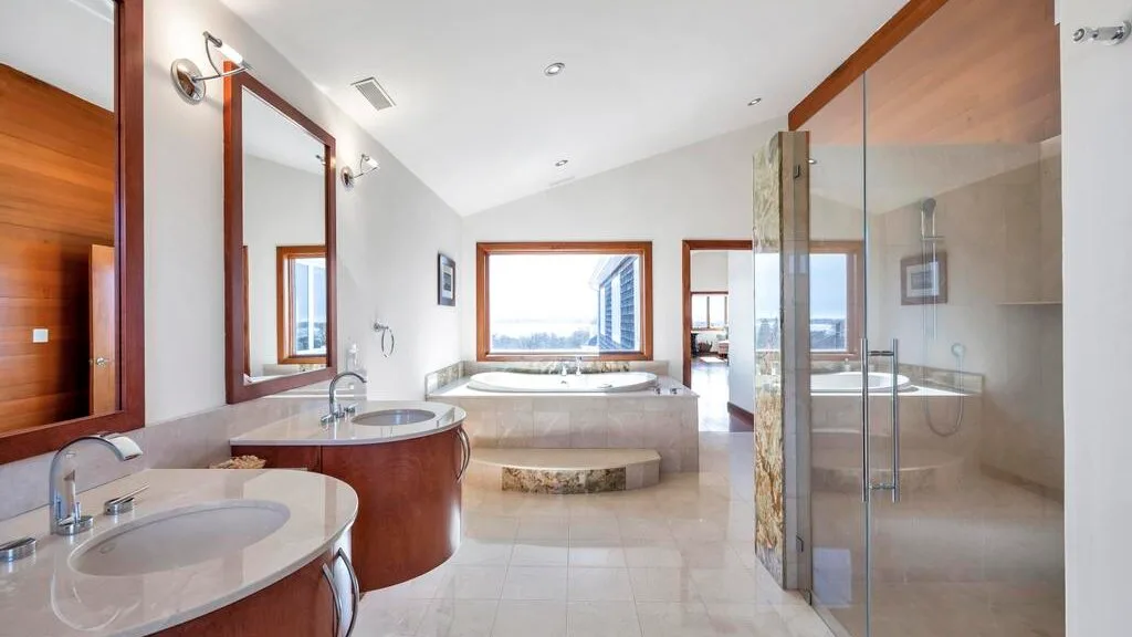 A spacious bathroom with a bathtub, vanity sinks, and a glass shower.