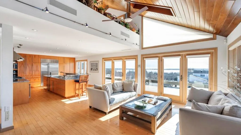 Una luminosa sala de estar y cocina de concepto abierto, con grandes ventanas frente al agua.