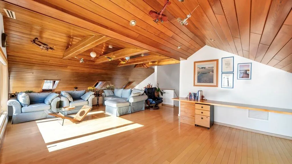 A bright living room with seating beneath a sloped wooden ceiling.
