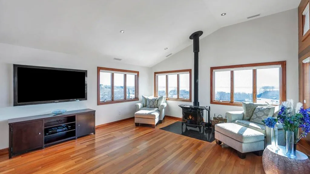 A bright living room with a television, seating, and a wood stove.