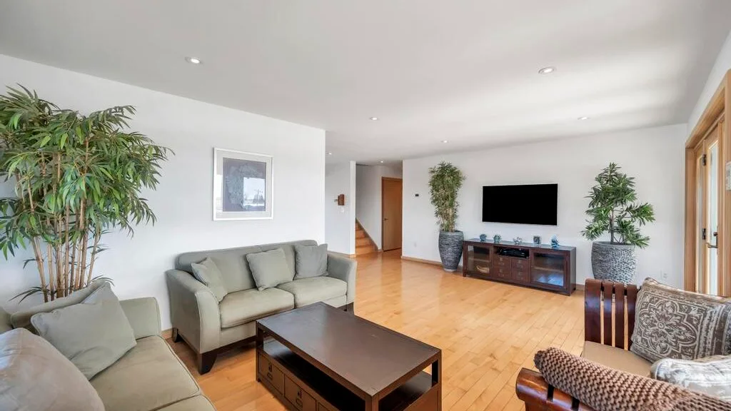 A bright living room with seating, a coffee table, and a television.