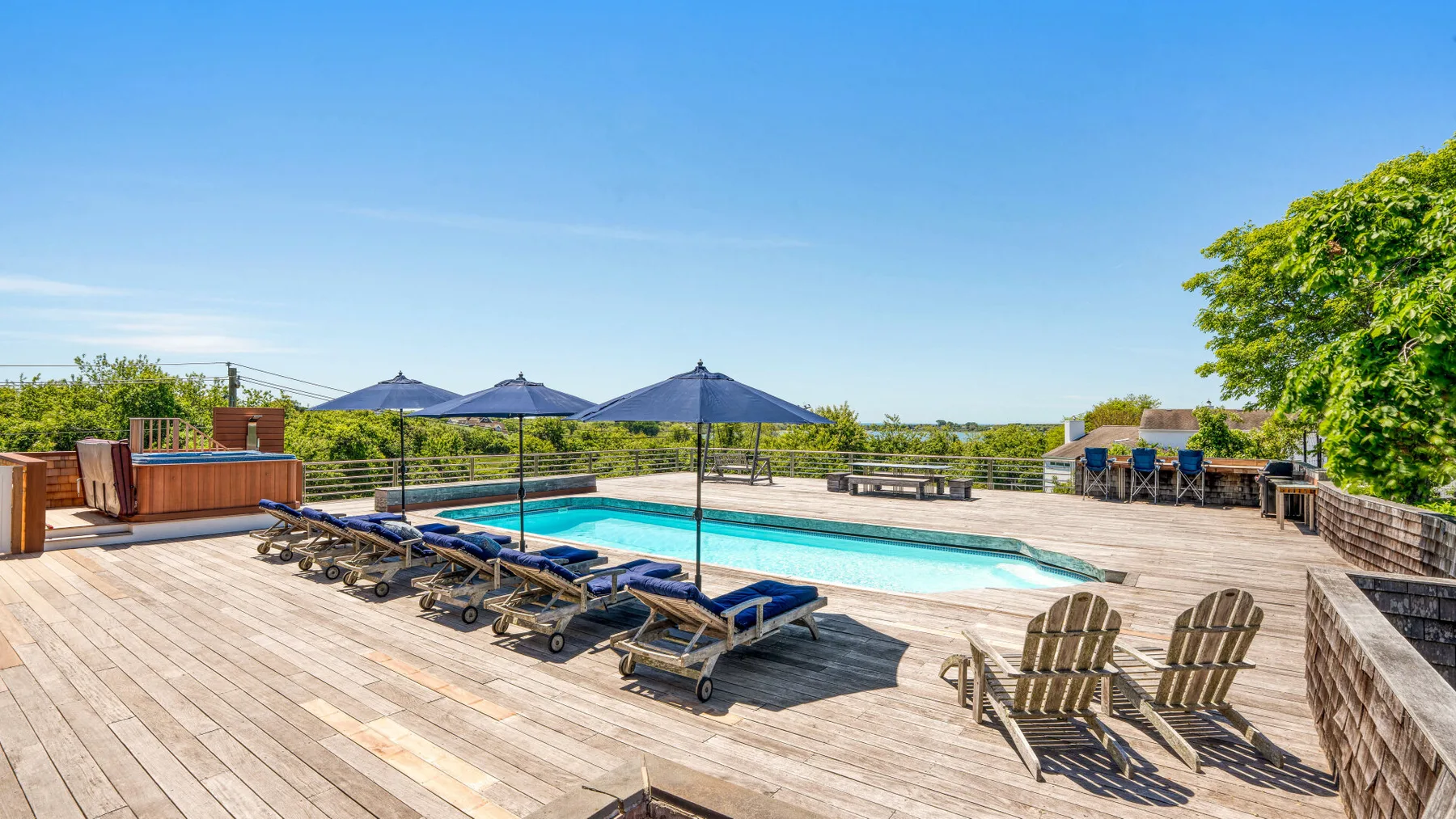 A rooftop pool sits on a broad wooden deck with lounge chairs.