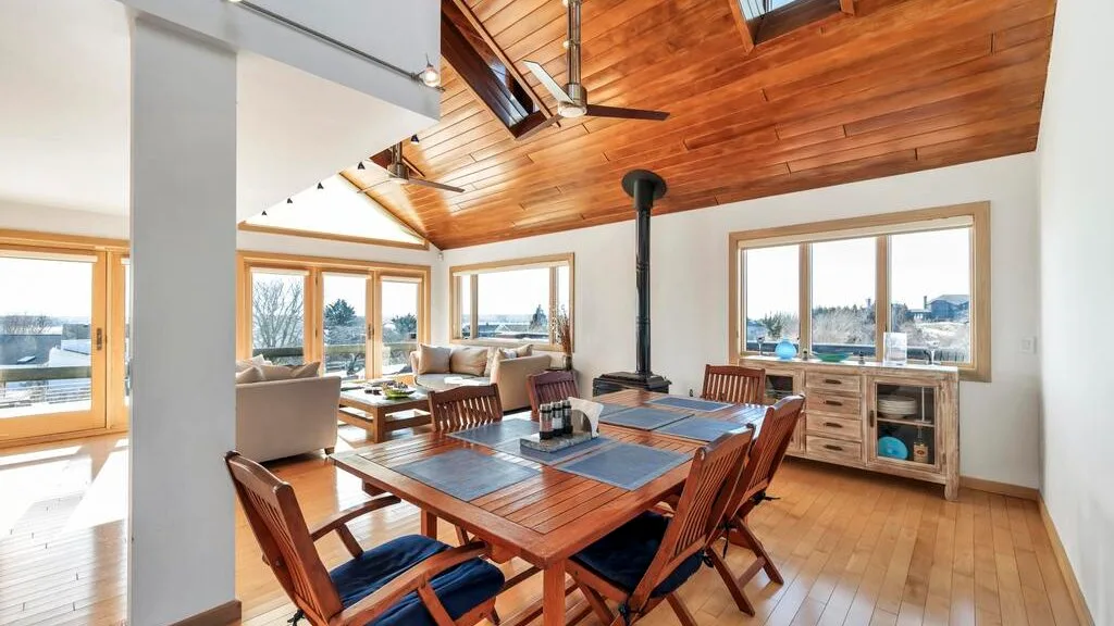 A bright dining area with a wooden table beneath a vaulted wood ceiling.