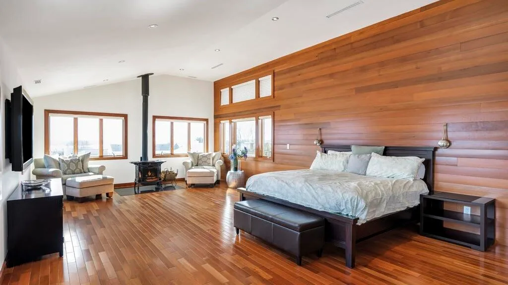 A bedroom with a large bed, wood-paneled walls, and a seating area.