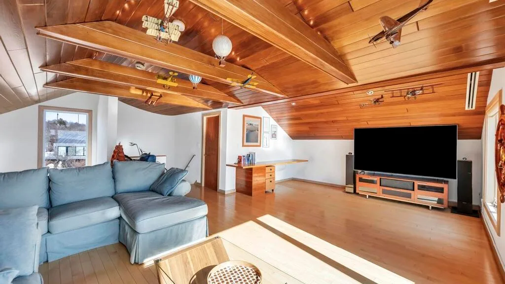 A living room with blue seating beneath a sloped wooden ceiling.