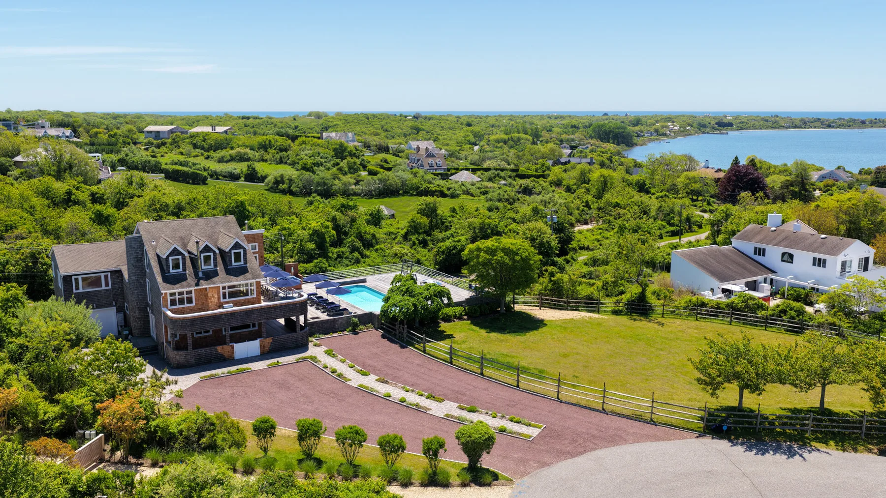 An aerial view shows a large house, swimming pool, and surrounding green landscape.