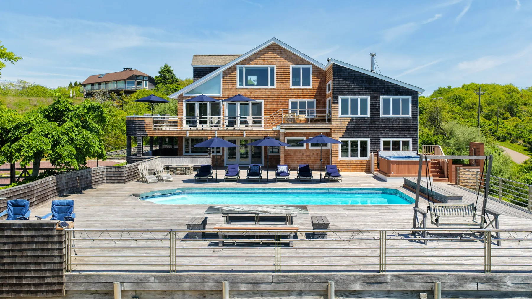 A large house overlooks a swimming pool and surrounding deck.