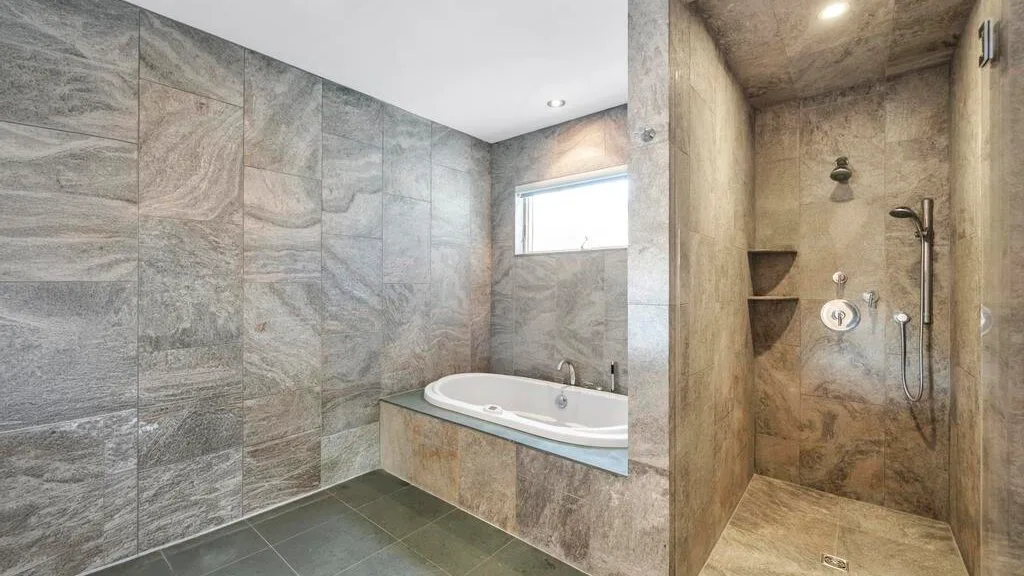 A tiled bathroom with a bathtub beside a separate shower area.