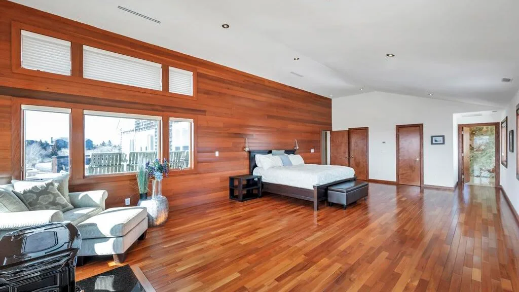 A bedroom with a bed, seating, and wood-paneled walls.
