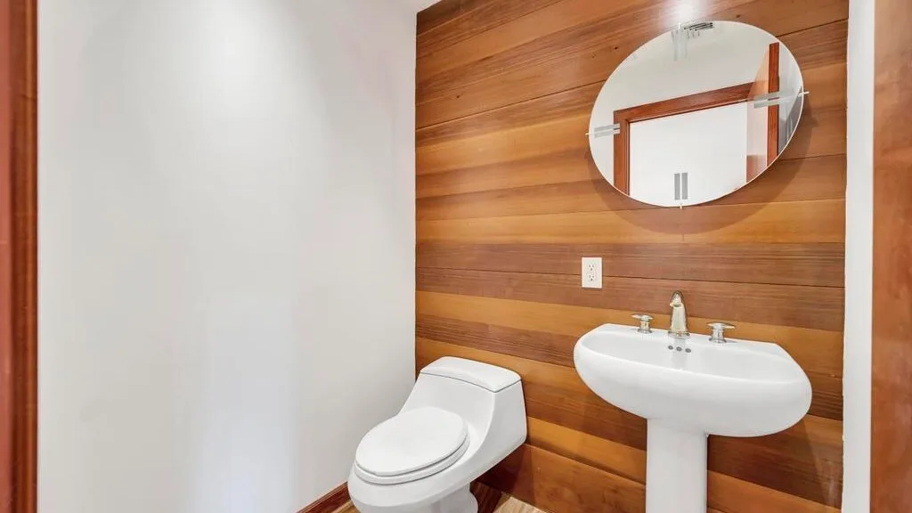 A bathroom with a toilet and sink against a wood-paneled wall.