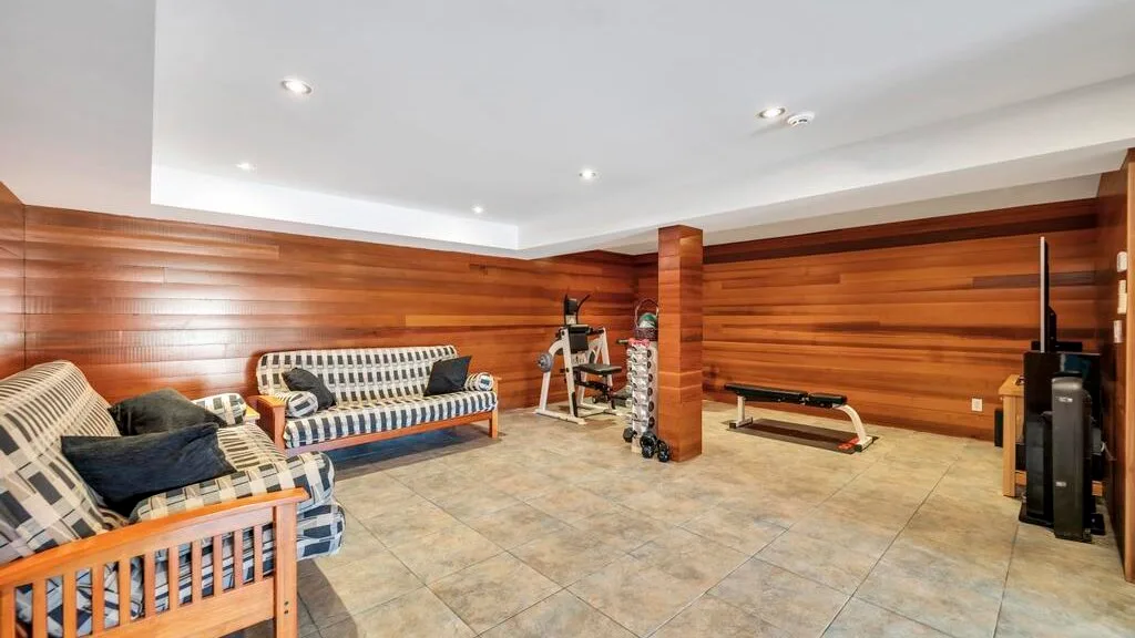 A wood-paneled recreation room with seating and exercise equipment.